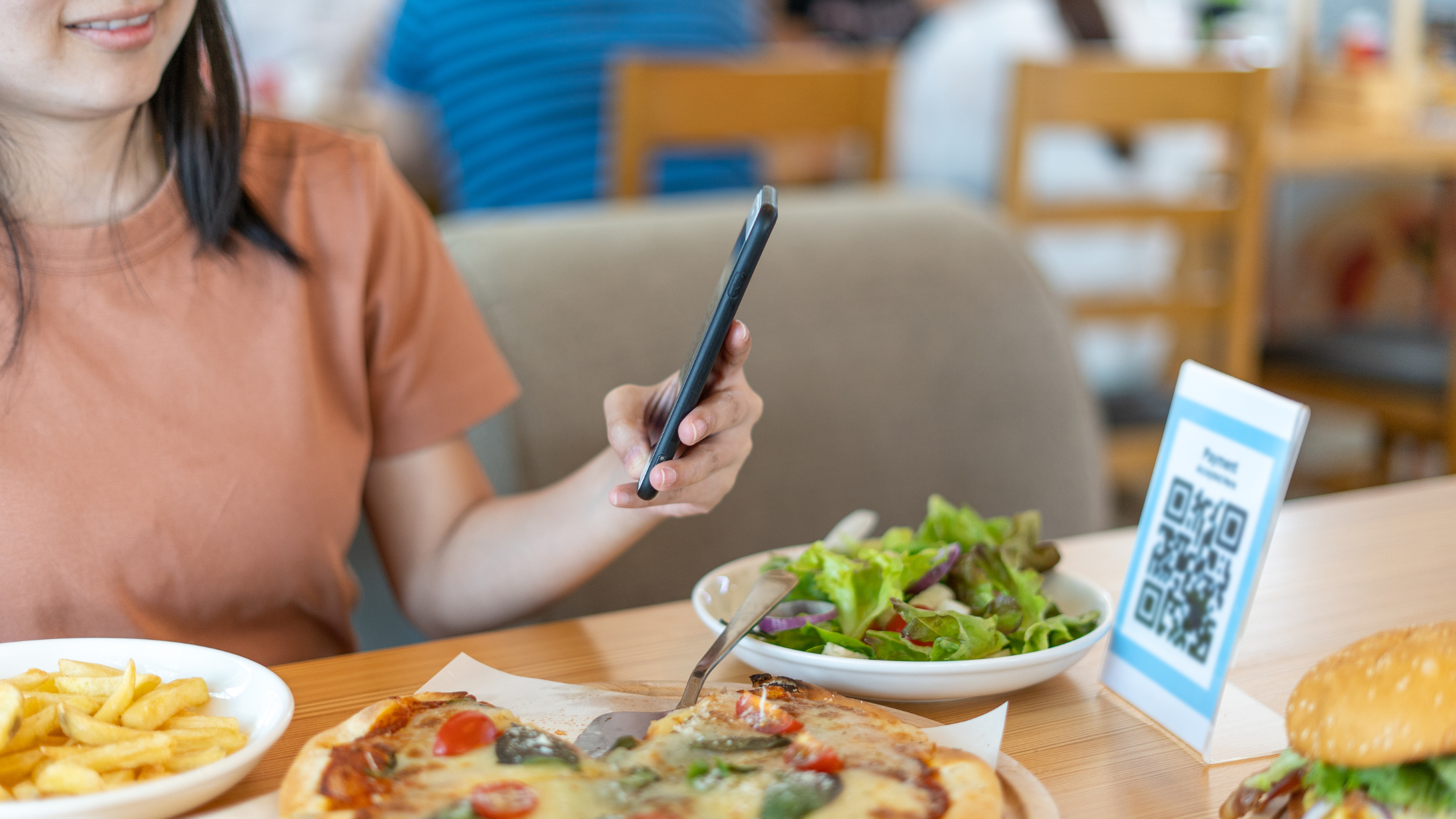 A woman at a restaurant scanning a QR code placard