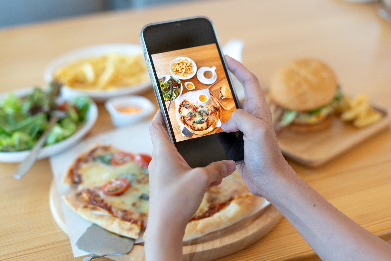 A person taking a photo of a food spread with their mobile phone